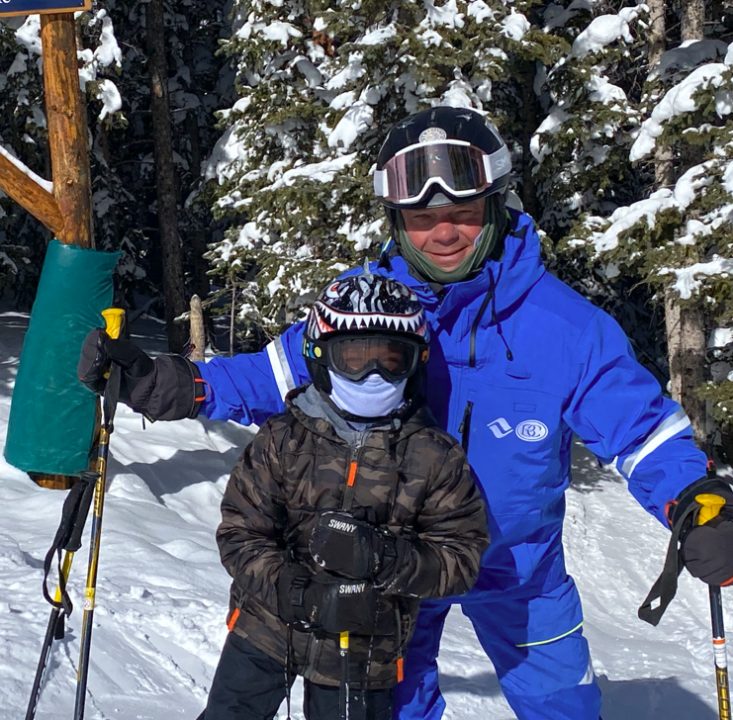 Brandon Causey and a child in ski gear on the mountain