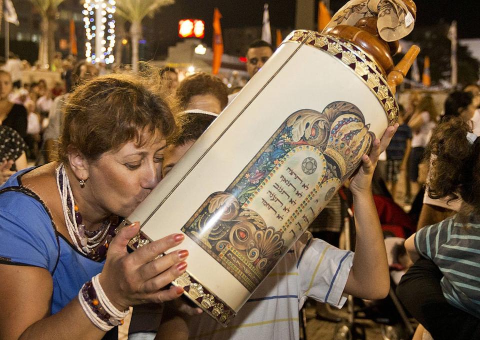 Simchat Torah joyously marks the end of the annual cycle of readings from the Torah. <a href="https://www.gettyimages.com/detail/news-photo/jewish-woman-kisses-a-torah-scroll-as-others-dance-and-sing-news-photo/181935443?phrase=simchat%20torah&adppopup=true" rel="nofollow noopener" target="_blank" data-ylk="slk:Jack Guez/AFP via Getty Images;elm:context_link;itc:0;sec:content-canvas" class="link ">Jack Guez/AFP via Getty Images</a>