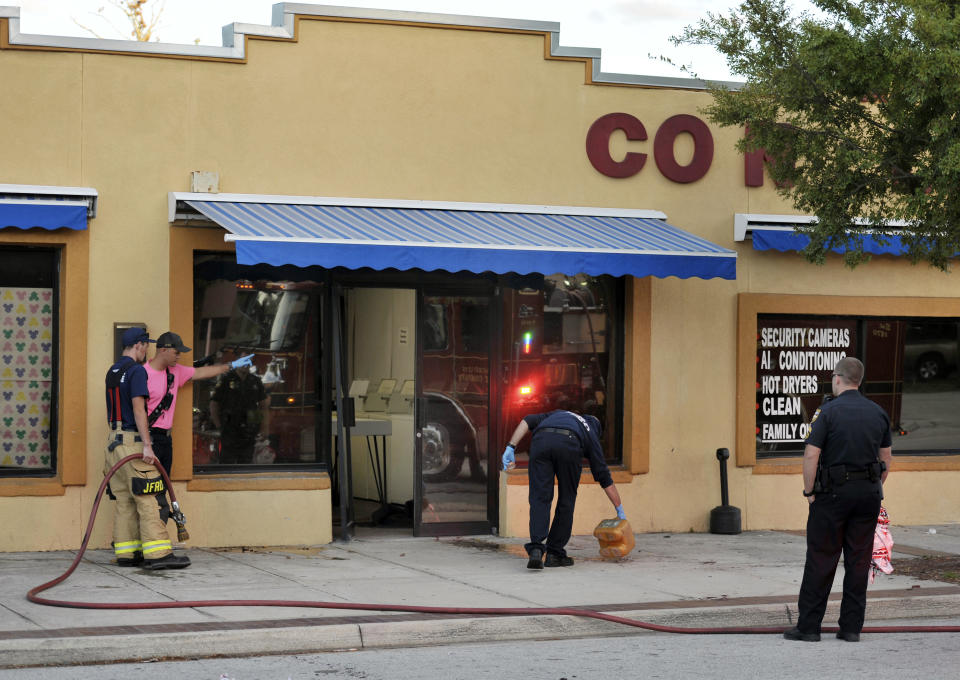 Jacksonville Fire and Rescue personnel use chemicals and hoses to clean the blood outside the Maytag Coin Laundry on A Philip Randolph Boulevard, Sunday, Oct. 21, 2018, in Jacksonville, Fla., after a street shooting earlier in the day, several blocks away from TIAA Bank Field where the Jacksonville Jaguars and Houston Texans played an NFL football game. (Bob Self/The Florida Times-Union via AP)