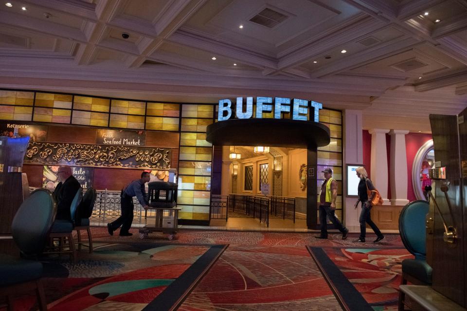 People moving around in front of a buffet entrance inside a well-lit, patterned establishment with a mix of modern and classic decor