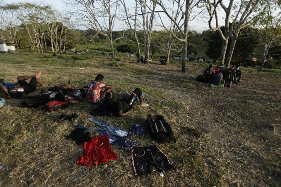 Haitian migrants sit on the grass at a migrant camp amid the new coronavirus pandemic in San Vicente, Darien province, Panama, Tuesday, Feb. 9, 2021. Panama is allowing hundreds of migrants stranded because of the pandemic, to move to the border with Costa Rica, after just reopening its land borders. (AP Photo/Arnulfo Franco)