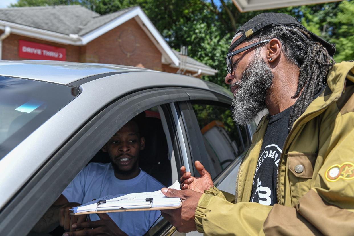 Olori Manns, right, helps Dionte Wynn-Parmer register to vote at a gas station in Akron. Manns, who will vote for the first time this November, is working for Freedom BLOC to register more new voters.