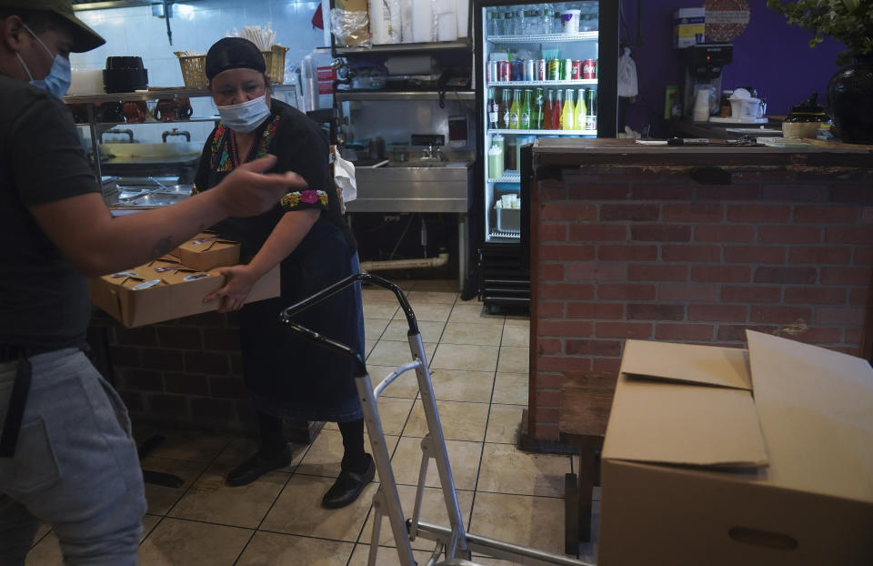 Natalia Méndez, right, prepares to load boxed meals she cooked at La Morada, an award winning Mexican restaurant she co-owns with her family in South Bronx, Wednesday Oct. 28, 2020, in New York. After recovering from COVID-19 symptoms, the family raised funds to reopen the restaurant, which they also turned into a soup kitchen serving 650 meals daily. (AP Photo/Bebeto Matthews)