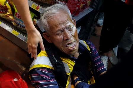 An anti-government protester is helped after being pepper-sprayed by the police near Yuen Long station, in Hong Kong