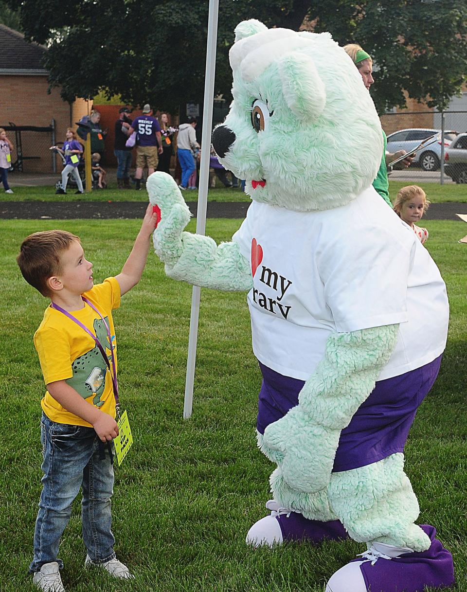 Graham Coffman, 4, gives a high-five to Sebring Public Library mascot Booker the Bear during the Literacy Under the Lights event Saturday, Sept. 16, 2023, at Schaefer-Davies Stadium in Sebring.
