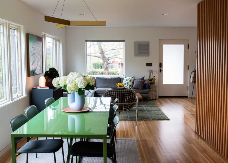 Brass pendant above green dining table in newly renovated dining room.