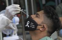 A health worker takes a swab sample to test for COVID-19 outside shopping mall in Mumbai, India, Saturday, April 3, 2021. (AP Photo/Rajanish Kakade)