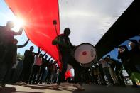 Man uses a drum as university students carry an Iraqi flag, during ongoing anti-government protests in Baghdad