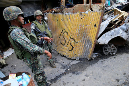 FILE PHOTO: Government soldiers stand on guard in front of damaged buildings as troops continue their assault on its 105th day of clearing operations against pro-IS militants who have seized control of large parts of Marawi City, Philippines September 4, 2017. REUTERS/Romeo Ranoco
