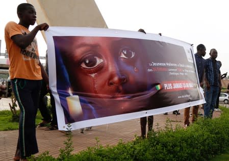 People carry a banner during a remembrance ceremony at the Monument de la Paix in Bamako