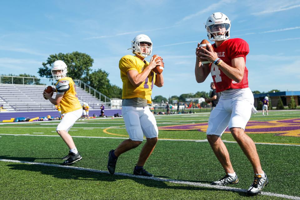 (From right) Warren De La Salle quarterbacks Brady Drogosh, Sante Gasperoni and Noah Poledink warm up during practice at school in Warren on Friday, Aug. 12, 2022.