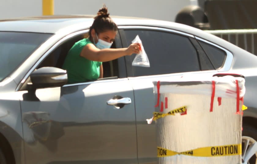 INGLEWOOD, CA - JULY 20, 2020 - - A woman deposits her coronavirus test in a bin at the COVID-19 testing site at The Forum parking lot in Inglewood on Monday, July 20, 2020. (Genaro Molina / Los Angeles Times)