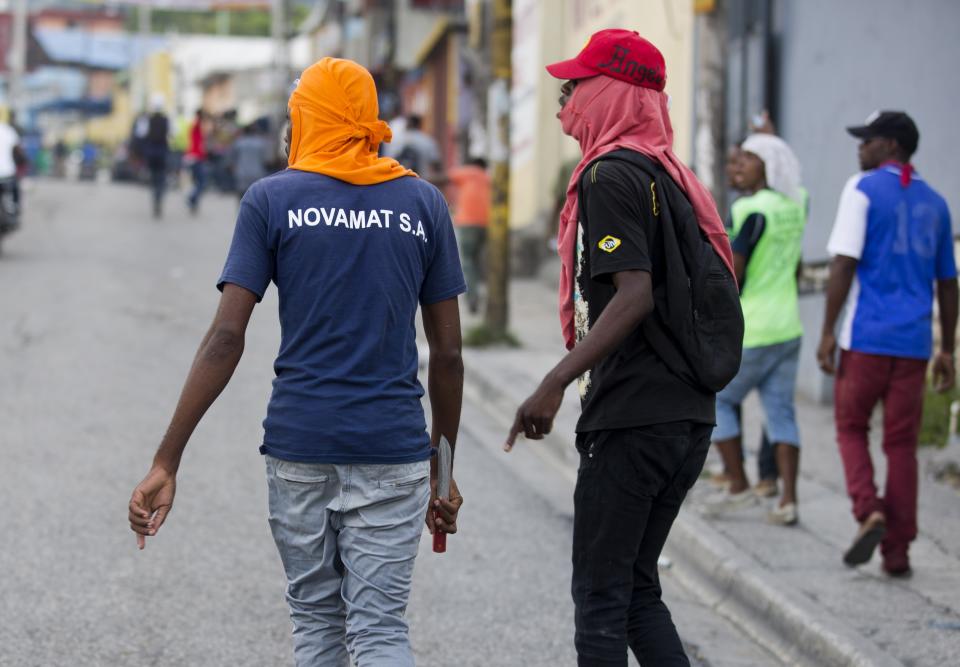 A demonstrator walks with a knife in his hand during a protest to demand the resignation of Haiti's president Jovenel Moise on the 216th anniversary of Battle of Vertieres in Port-au-Prince, Haiti, Monday, Nov. 18, 2019. At least four people were shot and wounded during a small protest in Haiti’s capital after a speech by embattled President Moise. A local journalist, a police officer and two protesters were rushed away with apparent bullet wounds. (AP Photo/Dieu Nalio Chery)