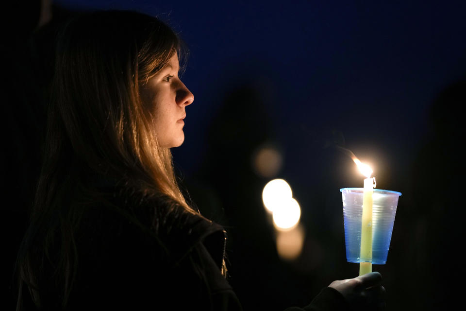 FILE - A local resident prays during a candlelight vigil following a shooting at Perry High School, Jan. 4, 2024, in Perry, Iowa. Teachers and staff in the rural Iowa district where the deadly school shooting took place could get bonuses if they don't quit their jobs under a new bill approved by lawmakers and sent to the governor. (AP Photo/Charlie Neibergall, file)