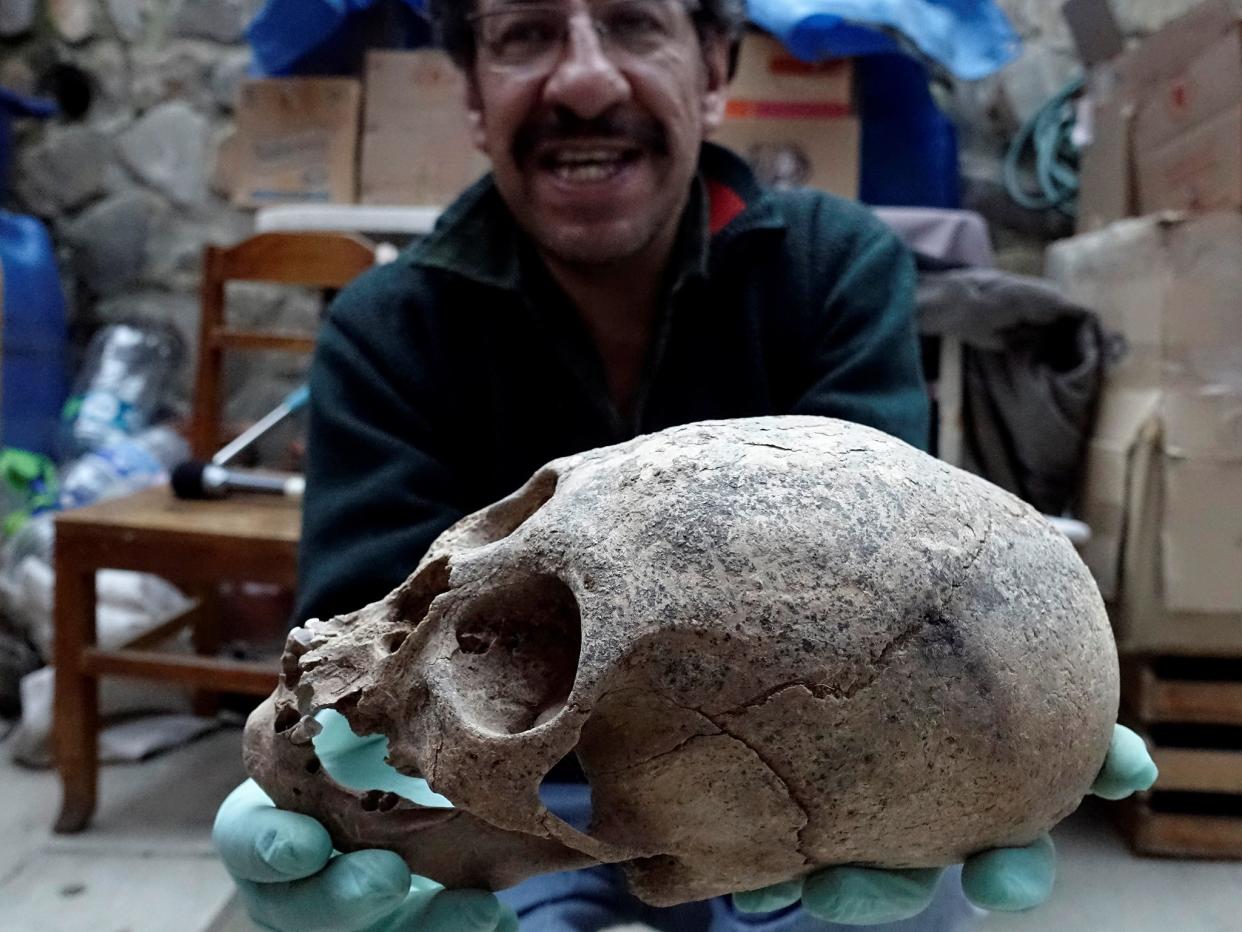 Archeologist Jedu Sagarnaga holds a skull as part of an archeological finding, dated approximately 500 years ago, in Mazo Cruz, near Viacha, Bolivia, November 12, 2018: REUTERS/David Mercado