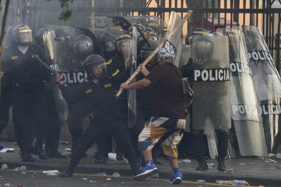 An anti-government protesters charges the police with a club during clashes in Lima, Peru, Thursday, Jan. 19, 2023. Protesters are seeking immediate elections, the resignation of President Dina Boluarte, the release from prison of ousted President Pedro Castillo and justice for demonstrators killed in clashes with police. (AP Photo/Martin Mejia)