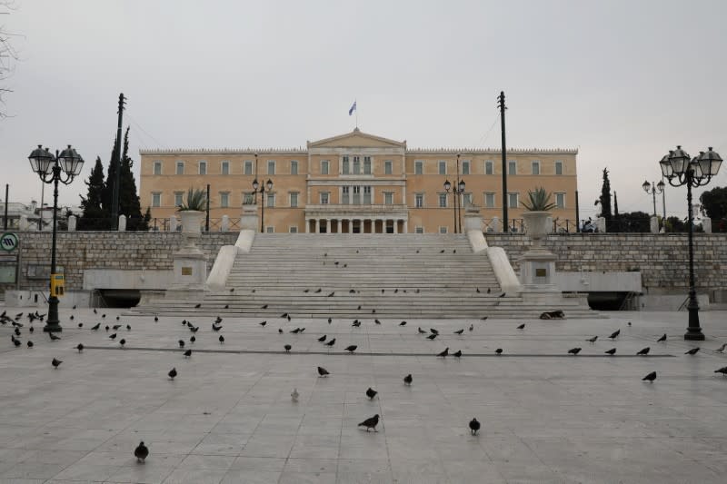 Pigeons flock on the empty Syntagma square with the parliament building in the background, following an outbreak of the coronavirus disease (COVID-19), in Athens