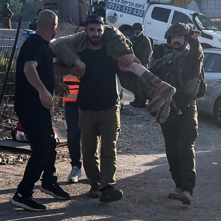 An Israeli soldier carries an injured comrade after projectiles were fired from Lebanon towards Israel, in Hurfeish on Wednesday