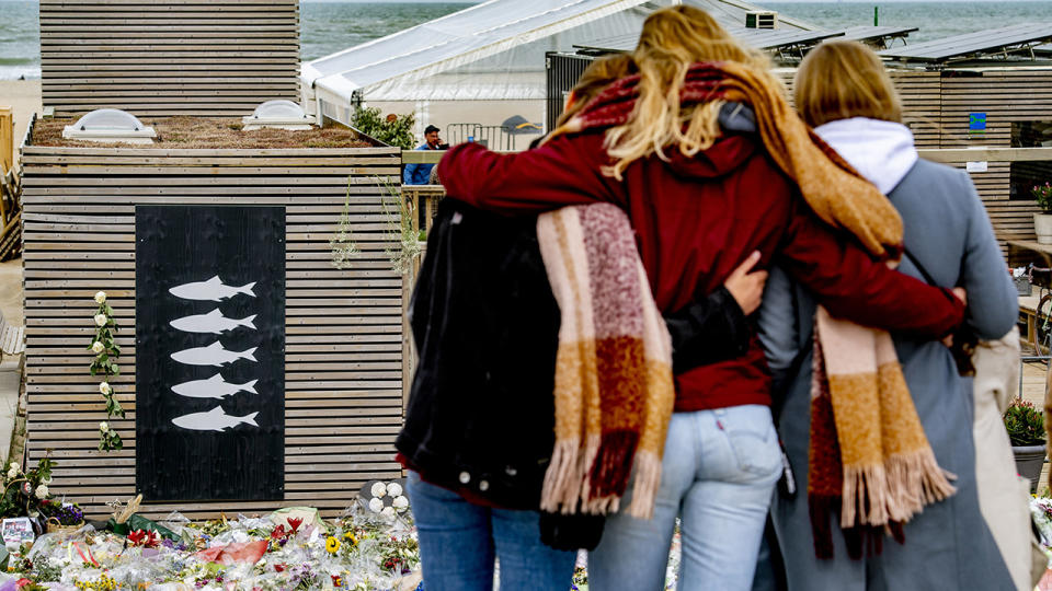 Locals, pictured here embracing next to a monument for the deceased surfers.