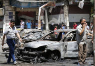 <p>Syrian men walk past charred vehicles at the site of a suicide bomb attack in the capital Damascus’ eastern Tahrir Square district, on July 2, 2017. (Louai Beshara/AFP/Getty Images) </p>