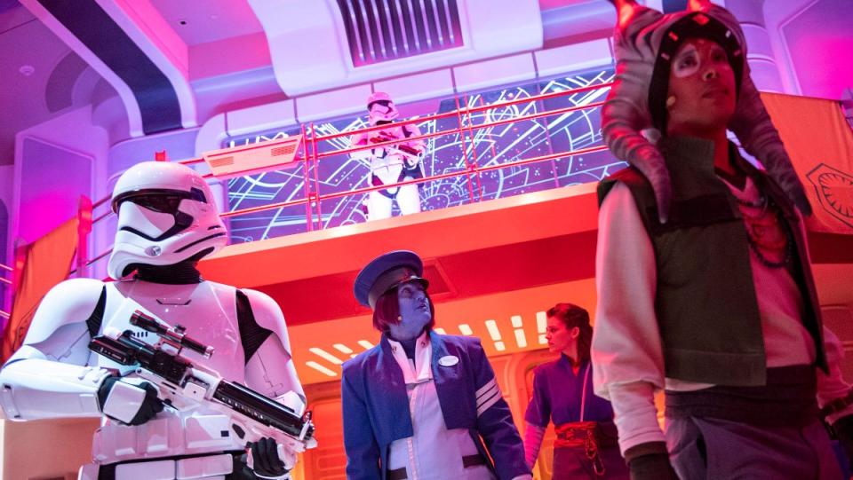 A stormtrooper looks over another trooper, Sandro, and the Captain of the Halcyon as part of Star Wars: Galactic Starcruiser