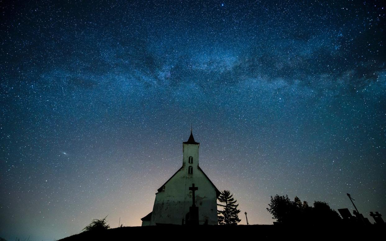 A church silhouetted below a belt of the Milky Way - EPA/PETER KOMKA