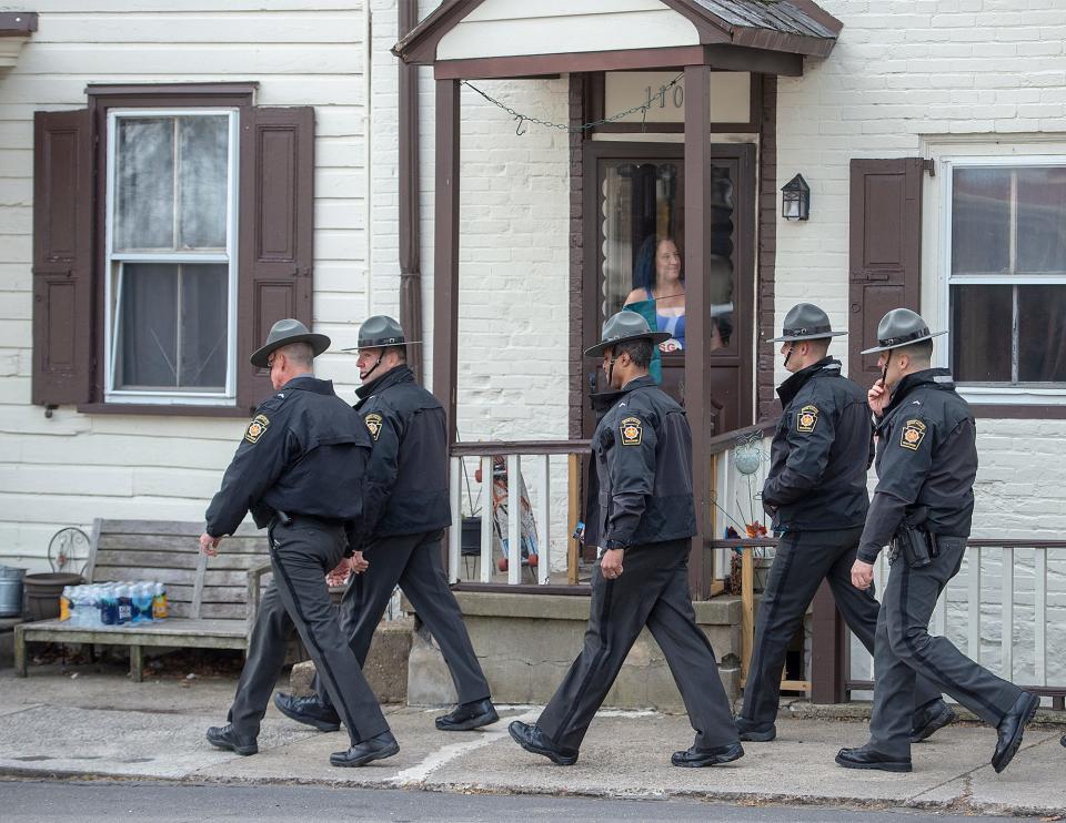 A group of Pennsylvania State Troopers walk by a resident on Radcliffe Street, after paying their respects during the viewing of Pennsylvania State Trooper Martin Mack III, held at the Wade Funeral Home in Bristol Borough, on Wednesday, March 30, 2022.