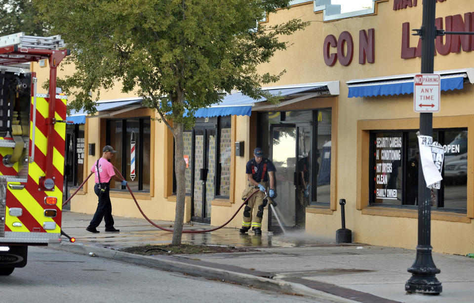 Jacksonville Fire and Rescue personnel use chemicals and hoses to clean the blood outside the Maytag Coin Laundry on A Philip Randolph Boulevard, Sunday, Oct. 21, 2018, in Jacksonville, Fla., after a street shooting earlier in the day, several blocks away from TIAA Bank Field where the Jacksonville Jaguars and Houston Texans played an NFL football game. (Bob Self/The Florida Times-Union via AP)