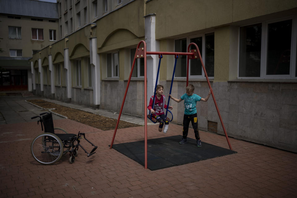 Yarik Stepanenko, de 11 años, impulsa a su hermana gemela Yana en un columpio frente a un hospital público el jueves 12 de mayo de 2022, en Leópolis, Ucrania. El 8 de abril, un misil cayó sobre la estación ferroviaria en la ciudad de Kramatorsk en el este de Ucrania donde Yana, Yarik y su madre Natasha planeaban tomar un tren de evacuados que se dirigía hacia el oeste y con el que esperaban alcanzar un lugar seguro. Yana perdió dos piernas, una arriba del tobillo, y la otra por encima de la espinilla. Natasha perdió la pierna izquierda debajo de la rodilla. Yarik permaneció en la estación en medio del caos del ataque y resultó ileso. Posteriormente se reencontró con su madre y su hermana. (AP Foto/Emilio Morenatti)