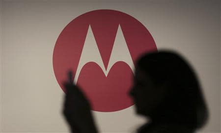A woman takes a picture in front of a Motorola logo before the worldwide presentation of the Moto G mobile phone in Sao Paulo November 13, 2013. REUTERS/Nacho Doce