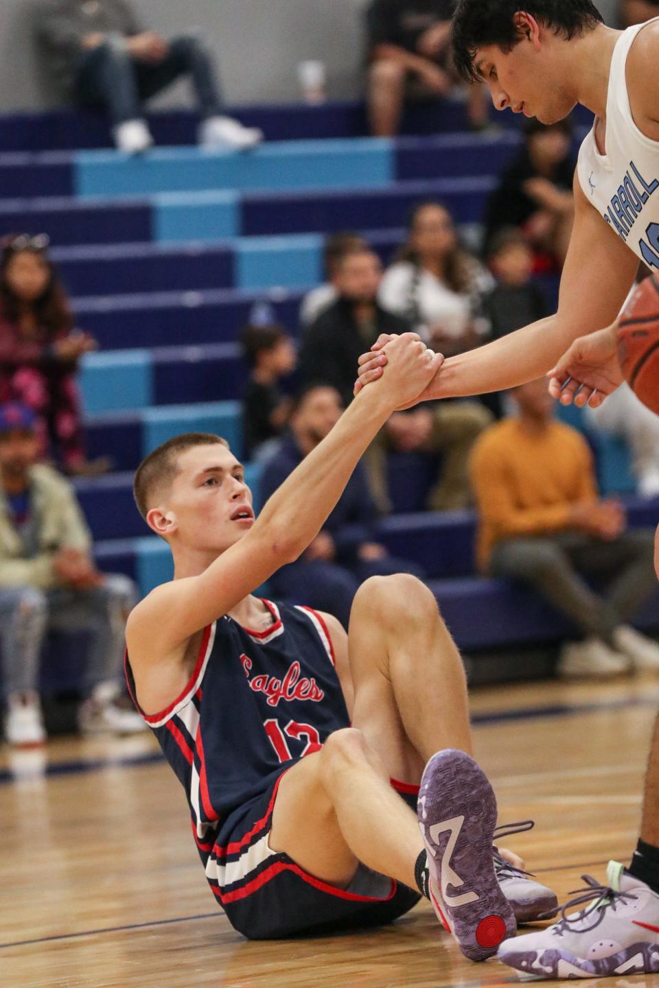 Carroll's Benny Hernandez helps Veterans Memorial's Dylan Cochran up at Carroll High School. The Eagles defeated the Tigers, 85-50, during the CCCA tournament on Dec. 2, 2022.
