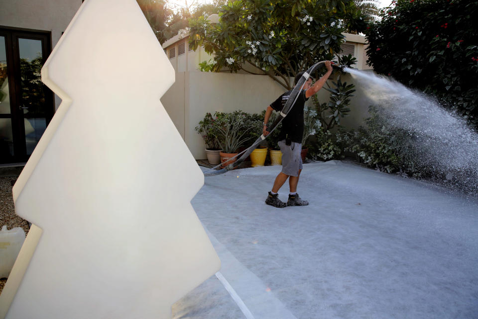 In this Saturday, Dec. 21, 2013 photo, Ben Elliott-Scott of Desert Snow company, a company which specializes in artificial snow, blasts trees with manmade flurries to turn them wintery white, a few hours ahead of a Christmas party at a private villa, in Dubai, United Arab Emirates. The Middle East’s brashest city is increasingly embracing the trappings of Christmas in a way that would be unthinkable in more conservative parts of the Muslim world. Christmas trees adorn shopping centers and residential neighborhoods, and high-end hotels try to outdo one another with extravagant and boozy holiday dinners. (AP Photo/Kamran Jebreili)