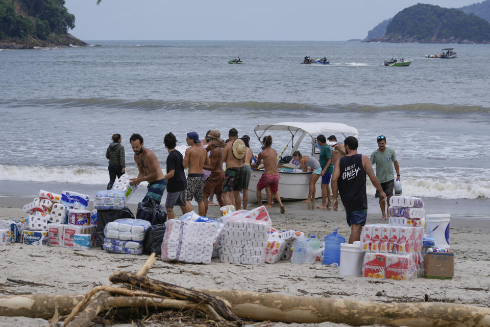 Volunteers unload donations on Barra do Sahi beach after deadly landslides triggered by heavy rain in the coastal city of Sao Sebastiao, Brazil, Wednesday, Feb. 22, 2023. (AP Photo/Andre Penner)