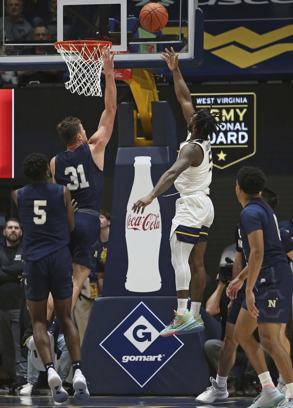 West Virginia guard Joe Toussaint (5) shoots while defended by Navy forward Daniel Deaver (31) during the first half of an NCAA college basketball game in Morgantown, W.Va., Wednesday, Dec. 7, 2022. (AP Photo/Kathleen Batten)