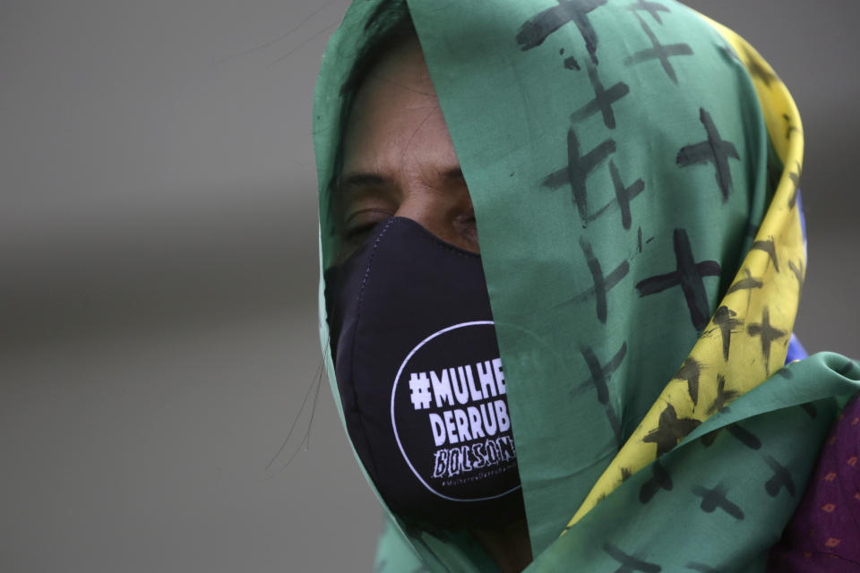 A women's movement activist wears a Brazilian flag on her head and a mask with a phrase written in Portuguese "Women Overthrow Bolsonaro," during a protest against the government's inefficiency in the face of the new coronavirus pandemic and the ongoing police brutality against blacks, in front of the National Congress, in Brasilia, Brazil, Thursday, July 2, 2020. (AP Photo/Eraldo Peres)