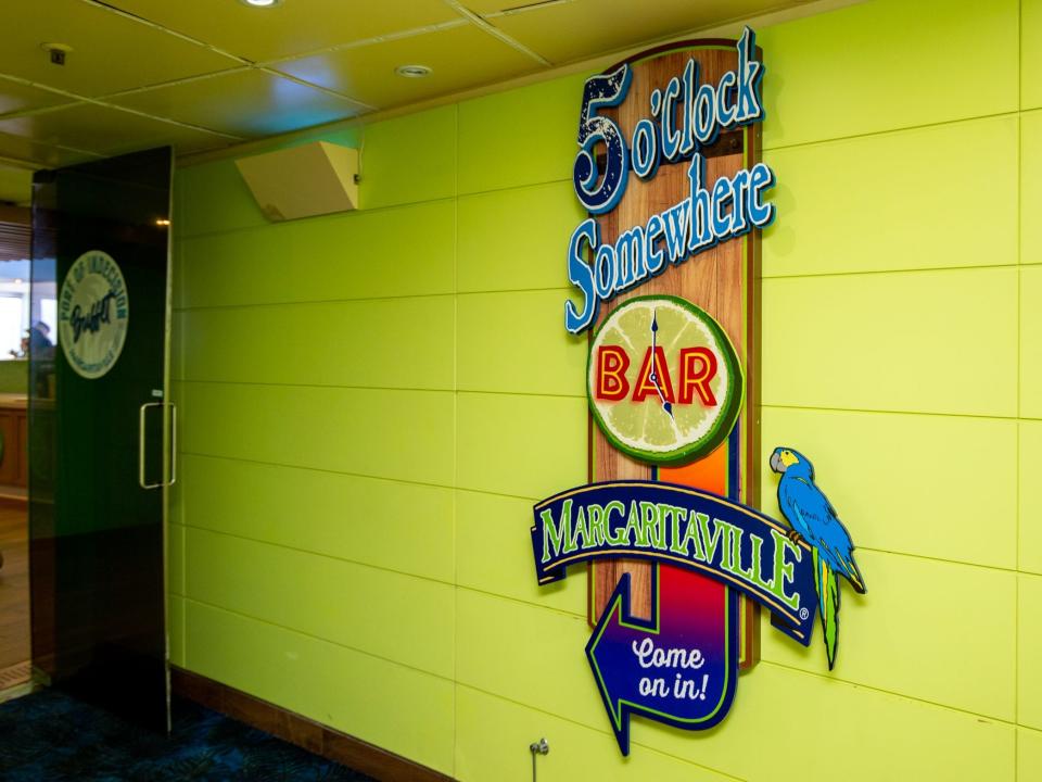 The 5 o'Clock Somewhere Bar sign on a bright green wall.