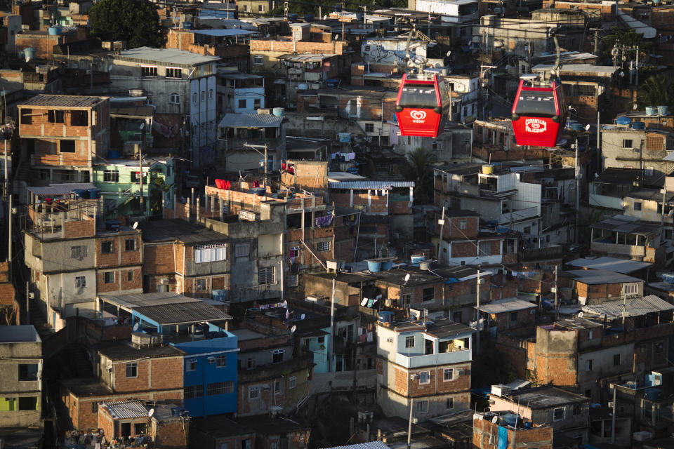 In this May 10, 2013 photo, cable-cars transporting commuters move over the Complexo do Alemao complex of shantytowns in Rio de Janeiro, Brazil. The cable-car system linking six of its hilltops over a 3.5-kilometer (2.3-mile) route has become a popular tourist attraction. (AP Photo/Felipe Dana)