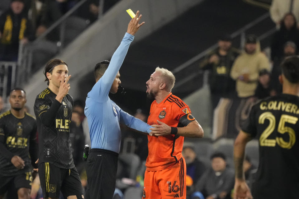 Houston Dynamo midfielder Héctor Herrera (16) reacts as he is shown a yellow card by referee Victor Rivas, center, during the second half in the MLS playoff Western Conference final soccer match against Los Angeles FC, Saturday, Dec. 2, 2023, in Los Angeles. (AP Photo/Marcio Jose Sanchez)