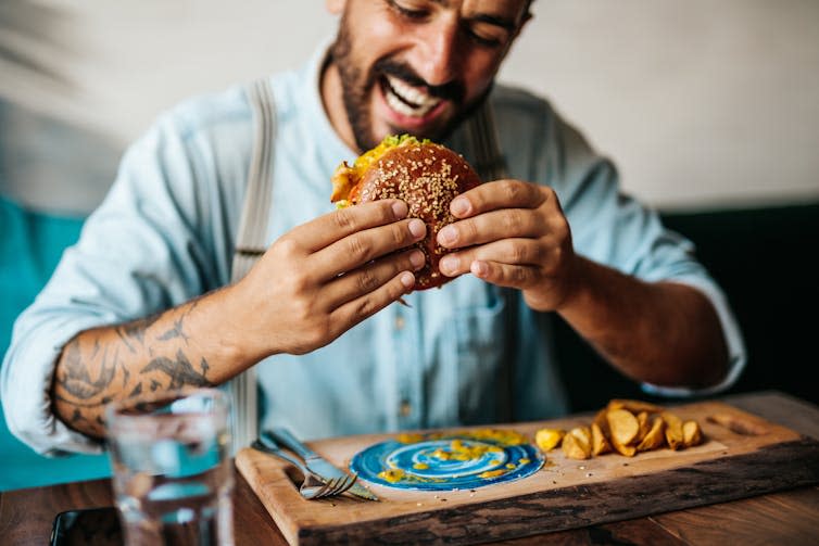 Man sitting in restaurant and enjoying a burger.