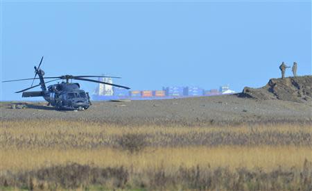 A Pave Hawk helicopter and military personnel attend the scene of a helicopter crash on the coast near the village of Cley next the Sea in Norfolk, eastern England January 8, 2014. REUTERS/Toby Melville