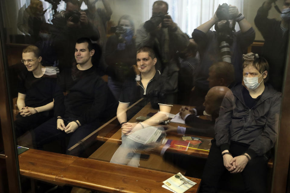 Members of the New Greatness group, who are charged with the organization of an extremist association, sit behind a glass in a courtroom prior to a court hearing in Moscow, Russia, Tuesday, July 14, 2020. Members of an opposition group dubbed New Greatness were arrested in 2018 on charges of creating an extremist group aiming to overthrow the government. The case was widely criticized as an example of politically motivated abuse anti-extremism laws. (AP Photo/Pavel Golovkin)