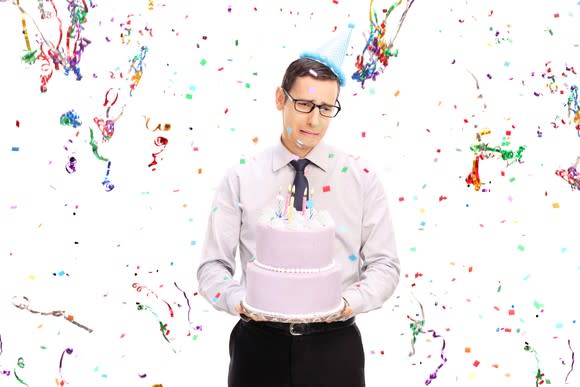 Sad man holding a cake at a party.