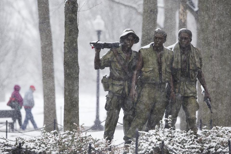 Visitors walk past the "The Three Soldiers" statue that is part of the Vietnam Veterans Memorial during a snow storm in Washington, Tuesday, March 25, 2014. The calendar may say it's spring, but the mid-Atlantic region is seeing snow again. The National Weather Service has issued a winter weather advisories for much of the region Tuesday. The advisories warn that periods of snow could make travel difficult, with slippery roads and reduced visibility. (AP Photo/ Evan Vucci)