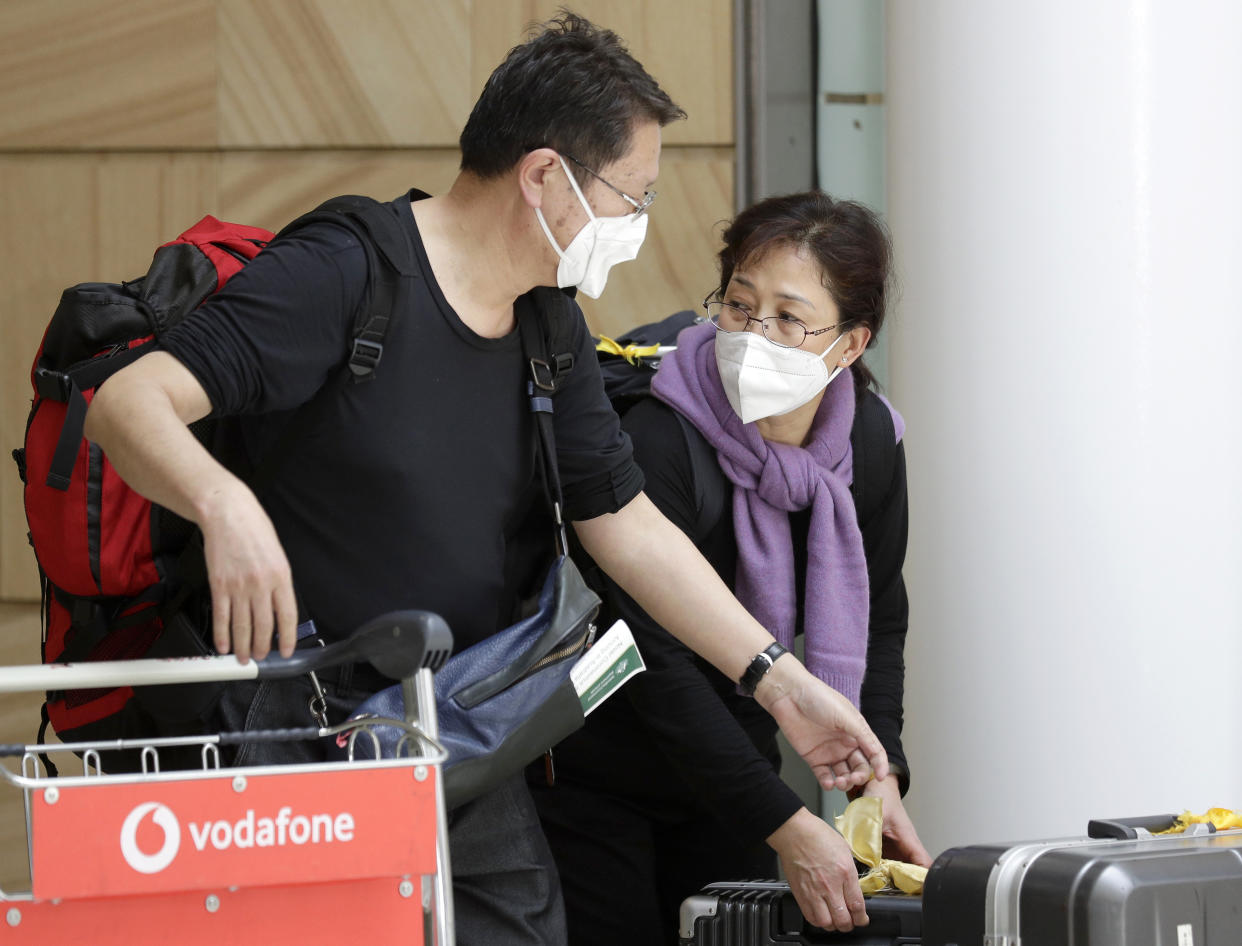 Travelers wearing face masks arrive in Sydney Thursday, Jan. 23, 2020, on a flight from Wuhan, China. China closed off a city of more than 11 million people as part of a radical effort to prevent the spread of a deadly virus that has sickened more than 500 people and has begun to spread to other cities and countries in the region. (AP Photo/Rick Rycroft)