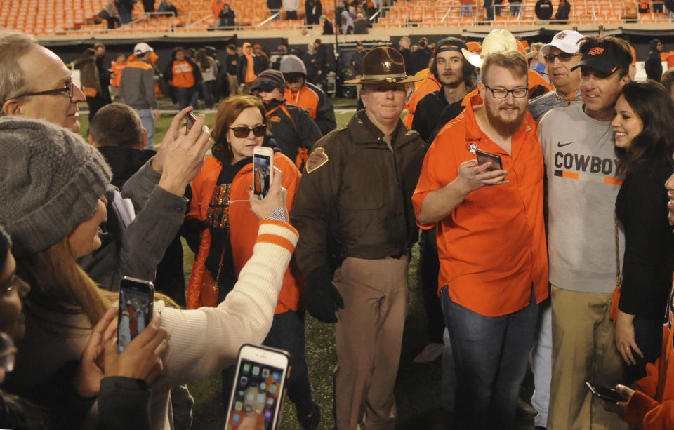 Oklahoma State head coach Mike Gundy celebrates with fans following the 45-41 upset over West Virginia at the end of an NCAA college football game in Stillwater, Okla., Saturday, Nov. 17, 2018. (AP Photo/Brody Schmidt)