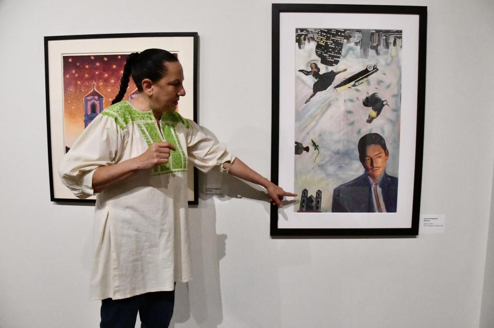 Mexican-American art collector Adrianna Abarca points to the spires of St. Cajetan's church in a painting rich in Chicano symbolism that's part of the Hecho en Colorado exhibit at El Pueblo History Museum in Pueblo, Colo.