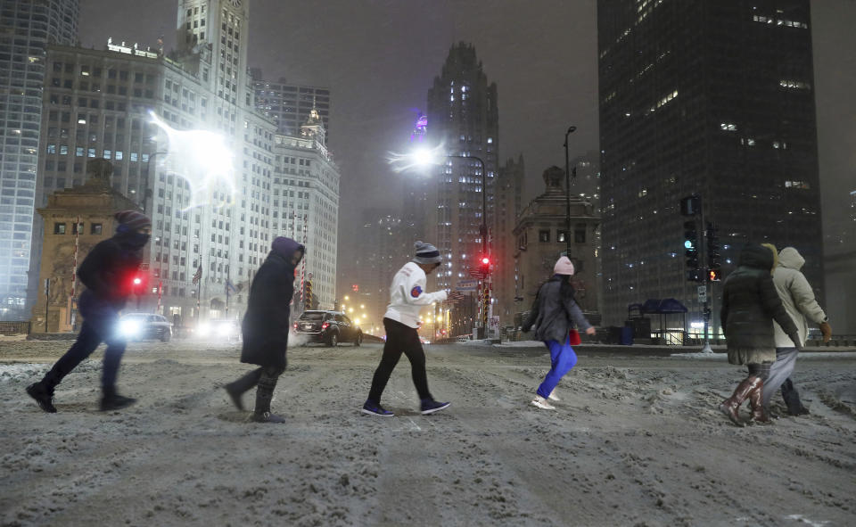 A group of people cross North Michigan Avenue during a snowstorm Friday, Jan. 17, 2020, in Chicago. A winter storm that has already caused trouble at airports in Chicago and Kansas City was expected to bring blizzard conditions to the Plains and Midwest on Saturday and could dump up to a foot of snow in parts of the Northeast on Sunday. (John J. Kim /Chicago Tribune via AP)