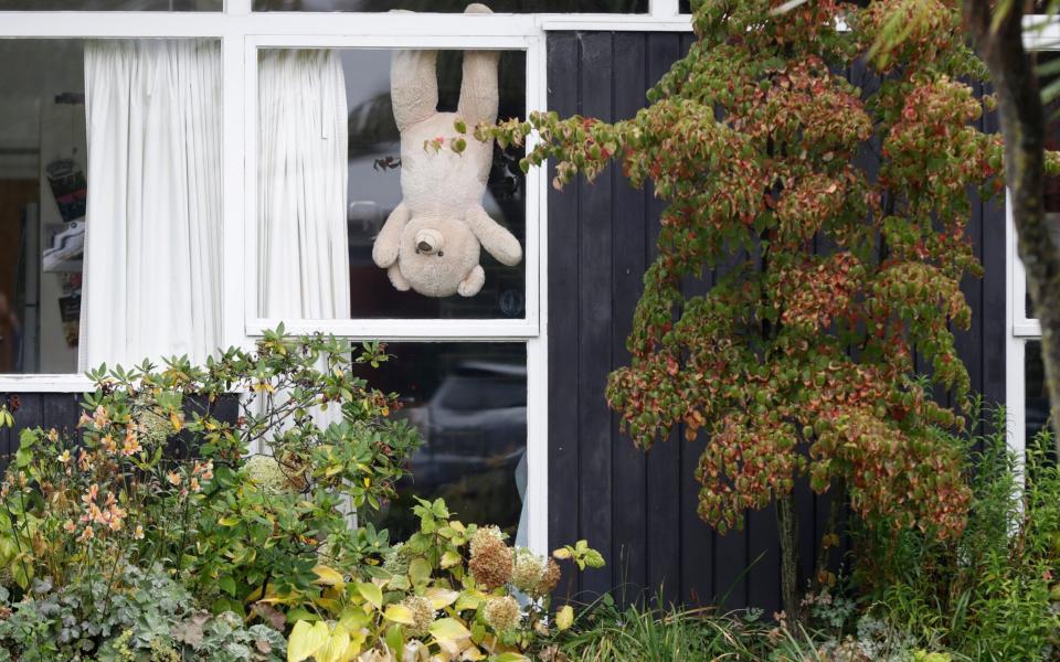 A teddy bear hangs upside down in a window of a house in Christchurch - AP Photo/Mark Baker