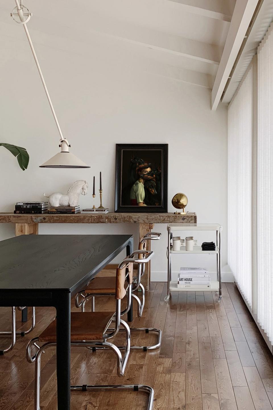 AFTER: Laura found an Anvia Counterbalance pendant from the 1950s on 1stDibs for the dining room, and paired it with vintage chairs and a table from Ethnicraft. The painting on the console table is Black from Aykut Aydogdu, Laura’s “favorite moment in the house.”