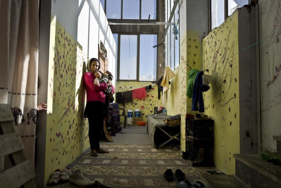 In this Monday, Dec. 26, 2016 photo, Parvaine Haideri, 30 and 5 months pregnant, an Afghan refugee from Kandahar, holds her 17-month old daughter Nazanin, while posing for a picture by the entrance of her shelter at the refugee camp of Oinofyta, Greece. "I have been waiting in Greece for the last 9 months after arriving from Kandahar, I hope they allow me to go to Denmark to be united with my family, I am a mother of three and the fourth is on the way", Haideri said. Squalid conditions and subfreezing temperatures in Greece’s migrant camps this winter are taking their toll on everyone living in them with expectant mothers and babies especially feel the brunt. (AP Photo/Muhammed Muheisen)